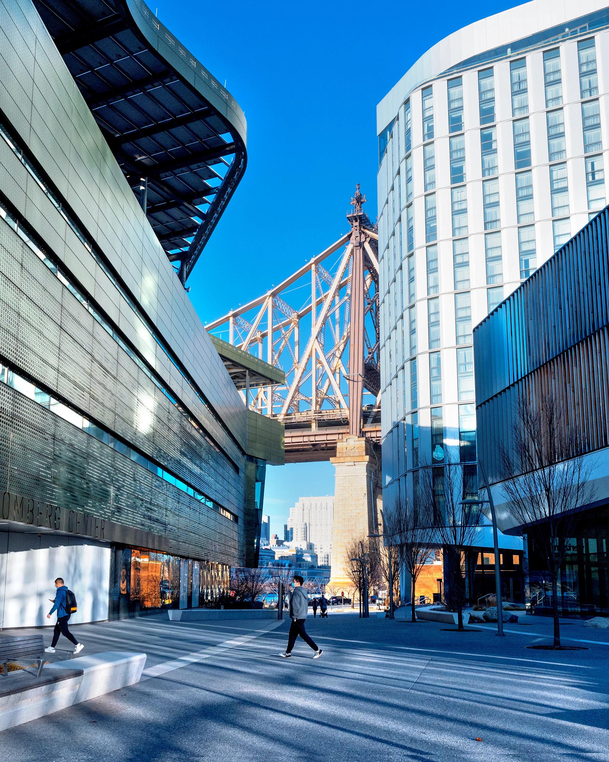 A photo of the Cornell Tech campus in New York City, looking down the main throughway with the Queensborough bridge in the background